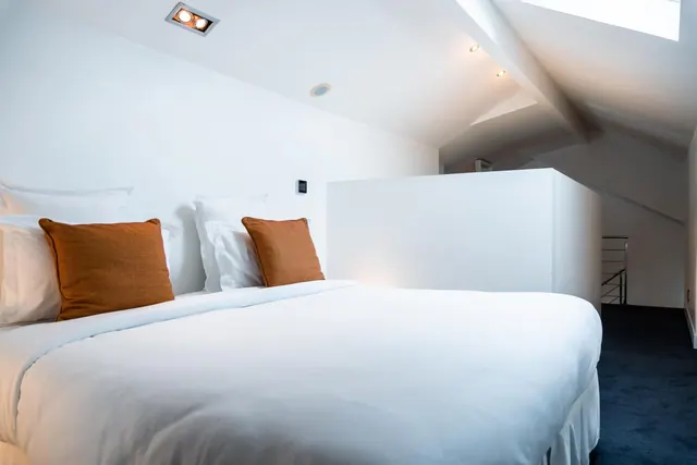 A bright modern bedroom with a neatly made double bed and white walls.