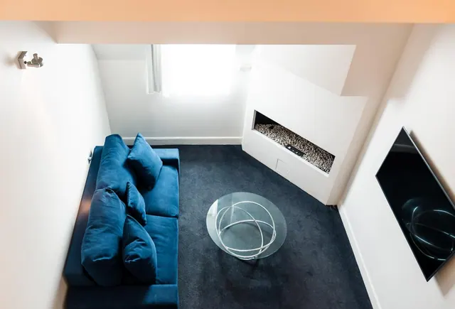 A blue sofa, glass coffee table and wall-mounted television furnish a bright modern living area.