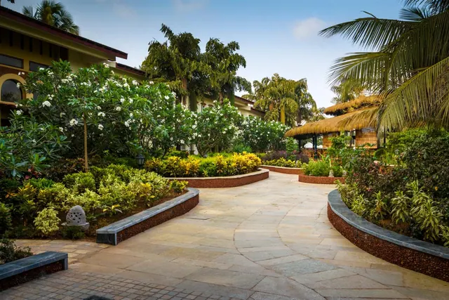 A landscaped tropical garden path leads between flowering plants and resort buildings.