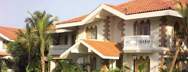 A heritage-style hotel building with terracotta roofs, arched windows, balconies and palm trees.