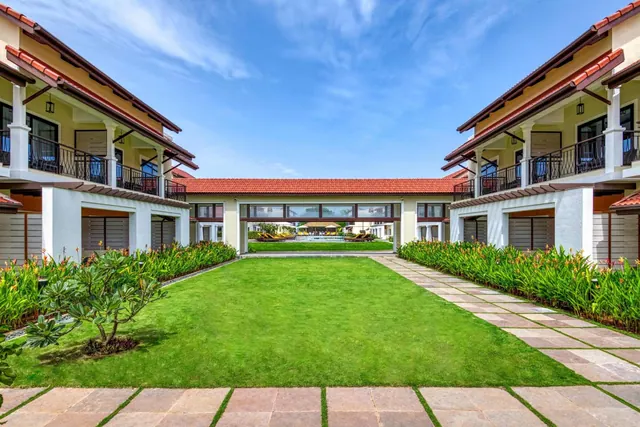 A landscaped courtyard lawn with tiled walkways and two-story resort buildings on either side.