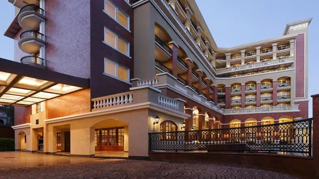 The hotel exterior has ornate balconies, arched entrances and a covered driveway.