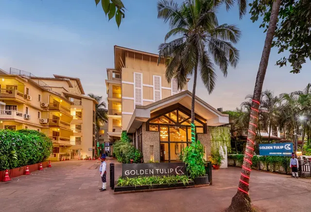 The Golden Tulip hotel entrance is shown among palm trees and landscaped grounds.