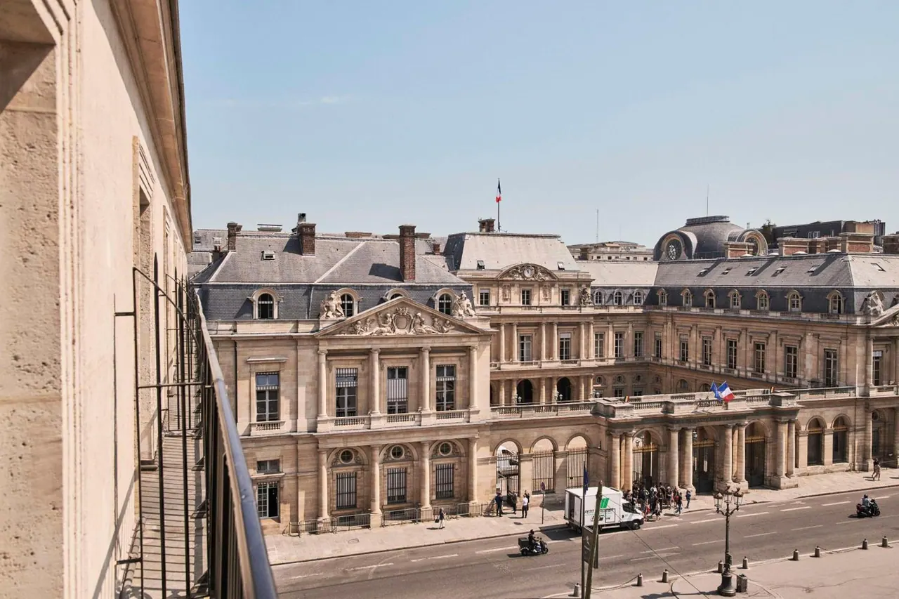 A balcony overlooks a grand historic Parisian building and the street below.