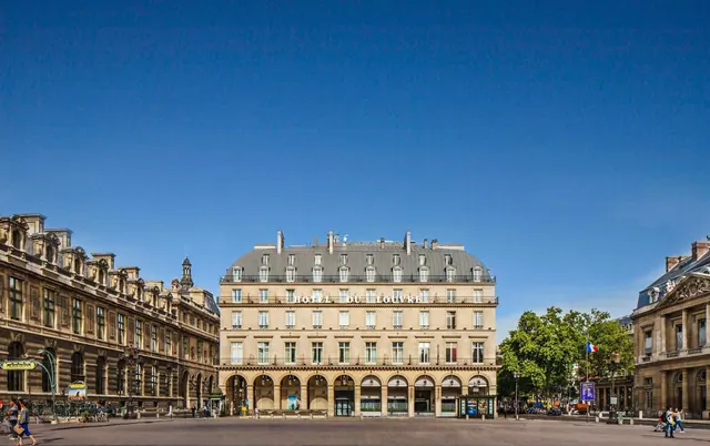 The Hotel du Louvre stands across a broad plaza among historic Parisian buildings.