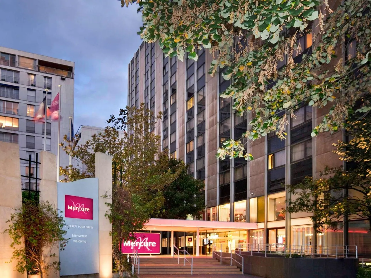 The Mercure hotel entrance is shown among landscaped trees and surrounding modern buildings.