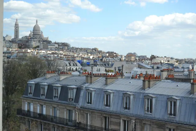 A view over Parisian rooftops toward the Basilica of the Sacré-Cœur de Montmartre.