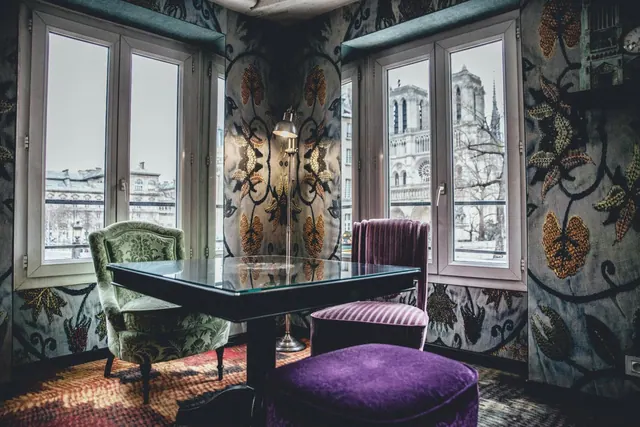 A richly patterned sitting room overlooks Notre-Dame de Paris through tall windows.