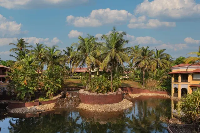 A tropical landscaped property surrounds a reflective waterway beneath a bright sky.