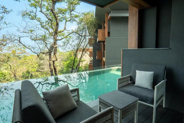 A furnished terrace overlooks a small private pool and surrounding trees.