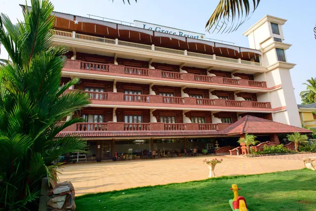 The resort building has red-tiled balconies, a covered entrance, and landscaped grounds with palm trees.