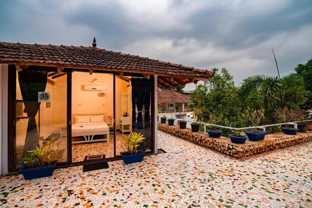 A tiled-roof building opens onto a landscaped courtyard with potted plants and patterned paving.