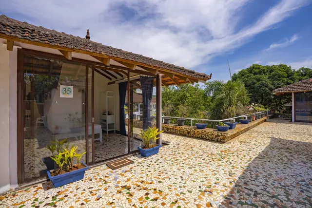 A tiled courtyard fronts a heritage-style building with glass doors, potted plants, and tiled roofs.