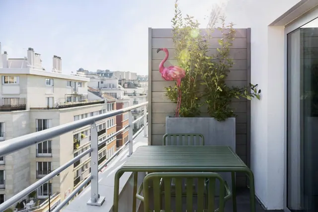 A furnished balcony overlooks the surrounding Paris apartment buildings.