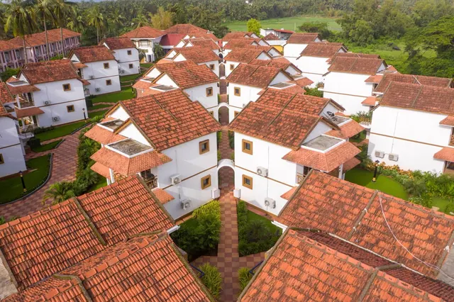 An aerial view shows white resort buildings with terracotta roofs arranged around landscaped courtyards.