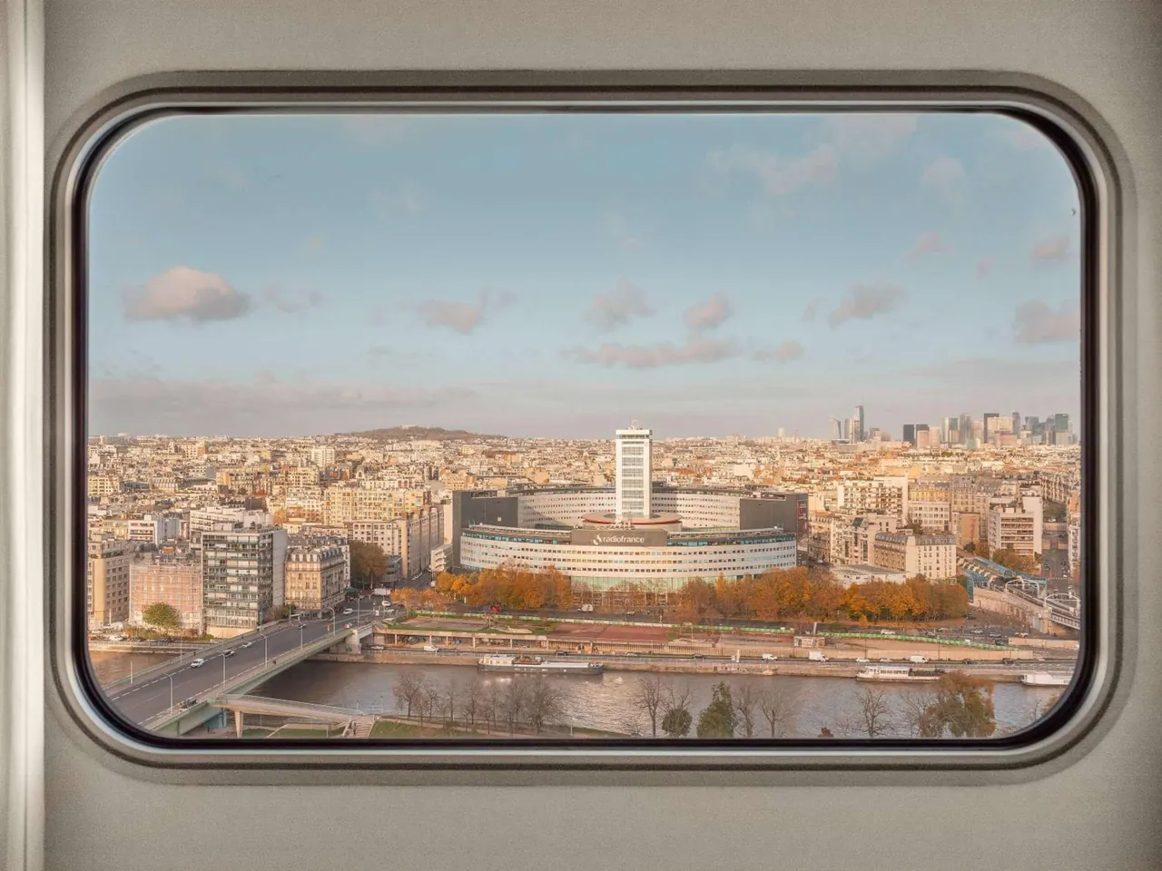 A broad city view across the Seine is framed by a large window.