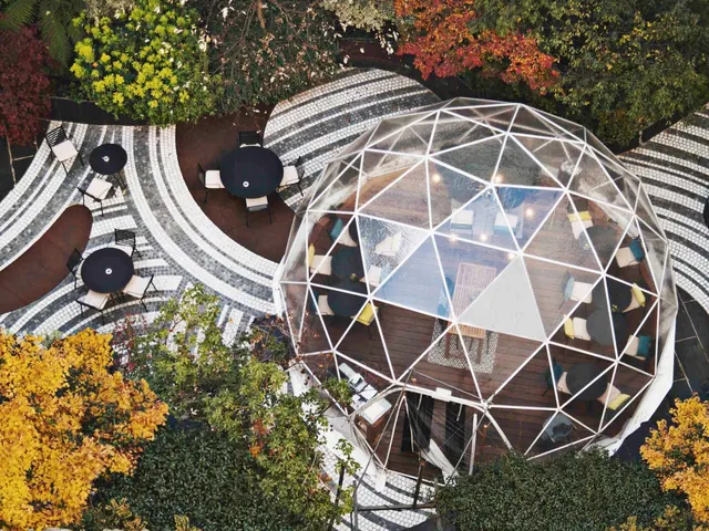 An overhead view shows a landscaped courtyard with curved patterned paving, outdoor tables, and a glass geodesic dome.
