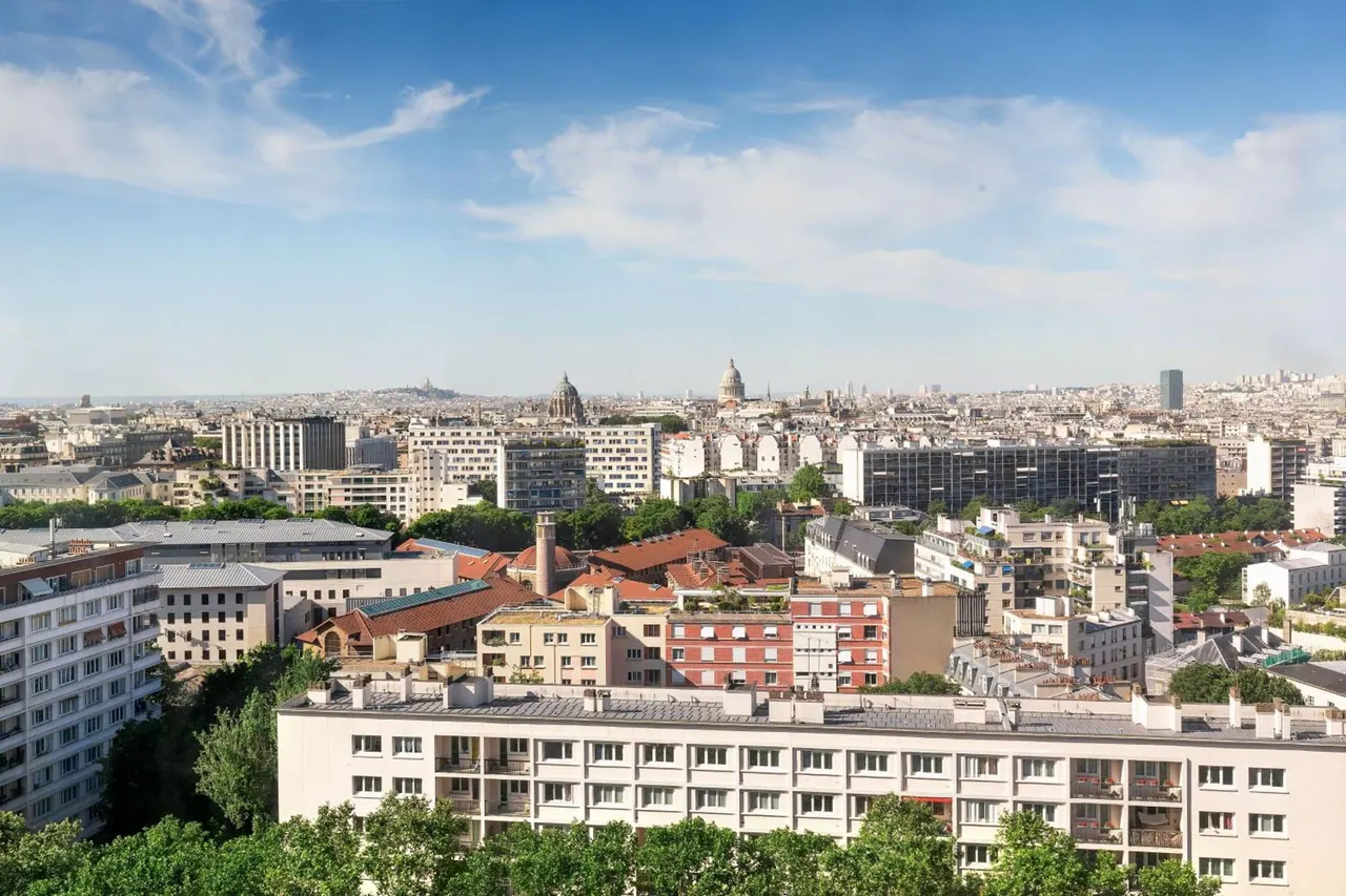 A wide view across Paris shows dense city buildings and the dome of Les Invalides.