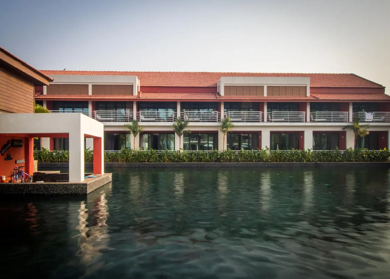 A large pool fronts a resort building with balconies and a pool bar.