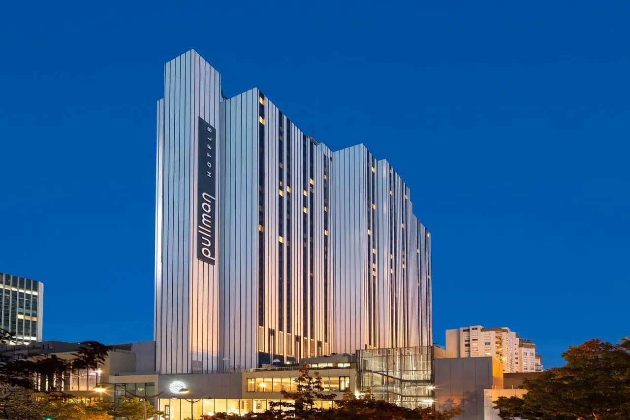 The illuminated Pullman hotel building stands against the evening sky.