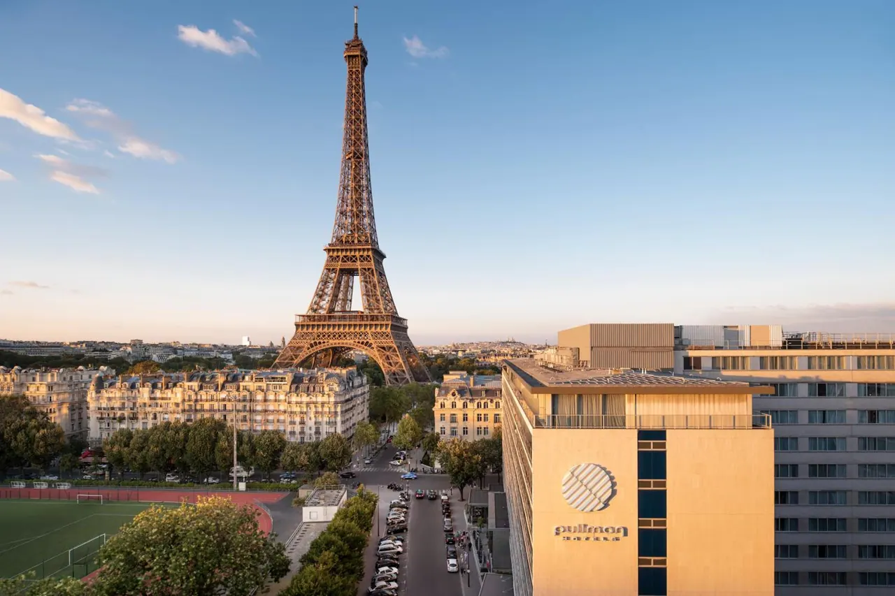 A panoramic city view shows the Eiffel Tower, Parisian buildings, streets, and a sports field.