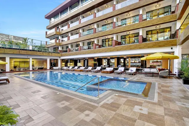 A large outdoor pool with a smaller adjoining pool, loungers and umbrellas sits in the hotel courtyard.