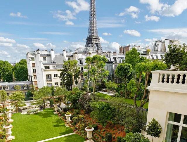 A landscaped garden and Parisian rooftops are seen with the Eiffel Tower in the background.