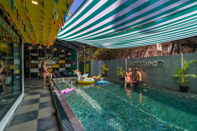 A small outdoor pool with inflatable floats sits beside a covered seating and bar area.