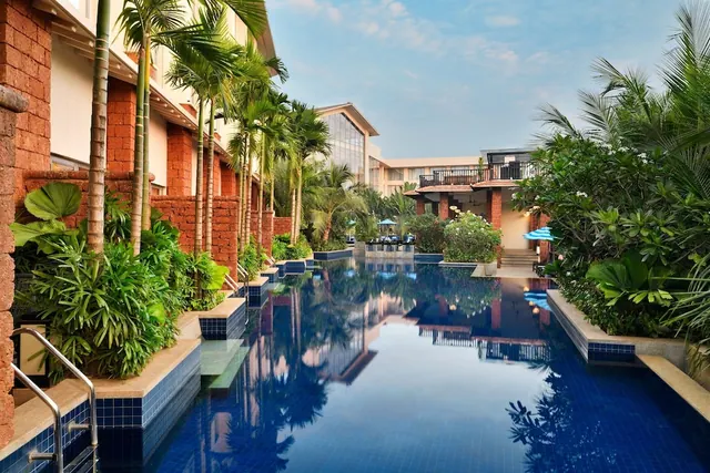 A large tiled pool is surrounded by tropical planting and resort buildings.