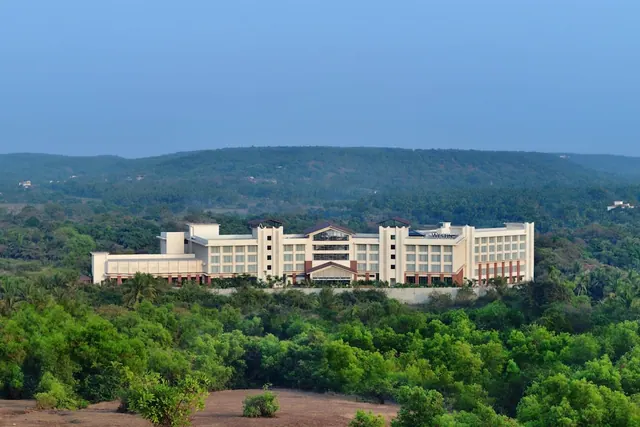A large Westin hotel building stands amid dense greenery with wooded hills behind it.