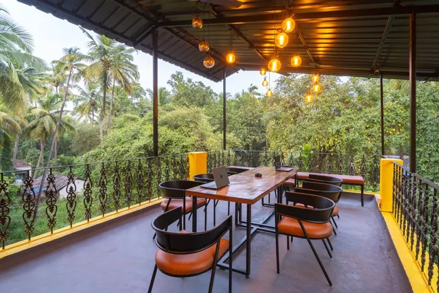 A covered terrace with dining tables and chairs overlooks lush tropical vegetation.